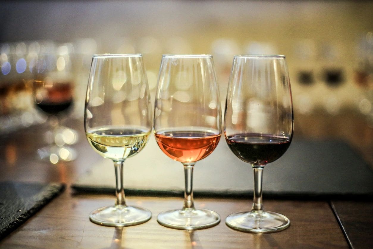 Three wine glasses are sitting on a table.